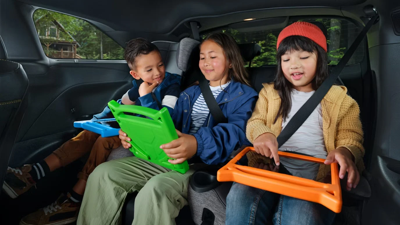 Three children with tablets side by side in the back of a 2026 Toyota Sienna